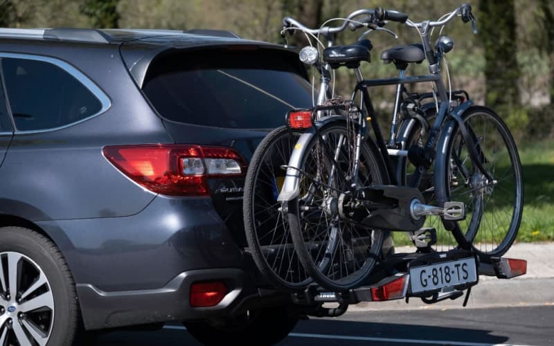 A hitch bike rack of a car carries two bicycles