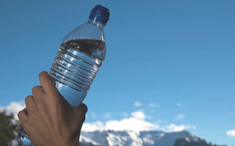 hand holding a bottle of water under the clear blue sky
